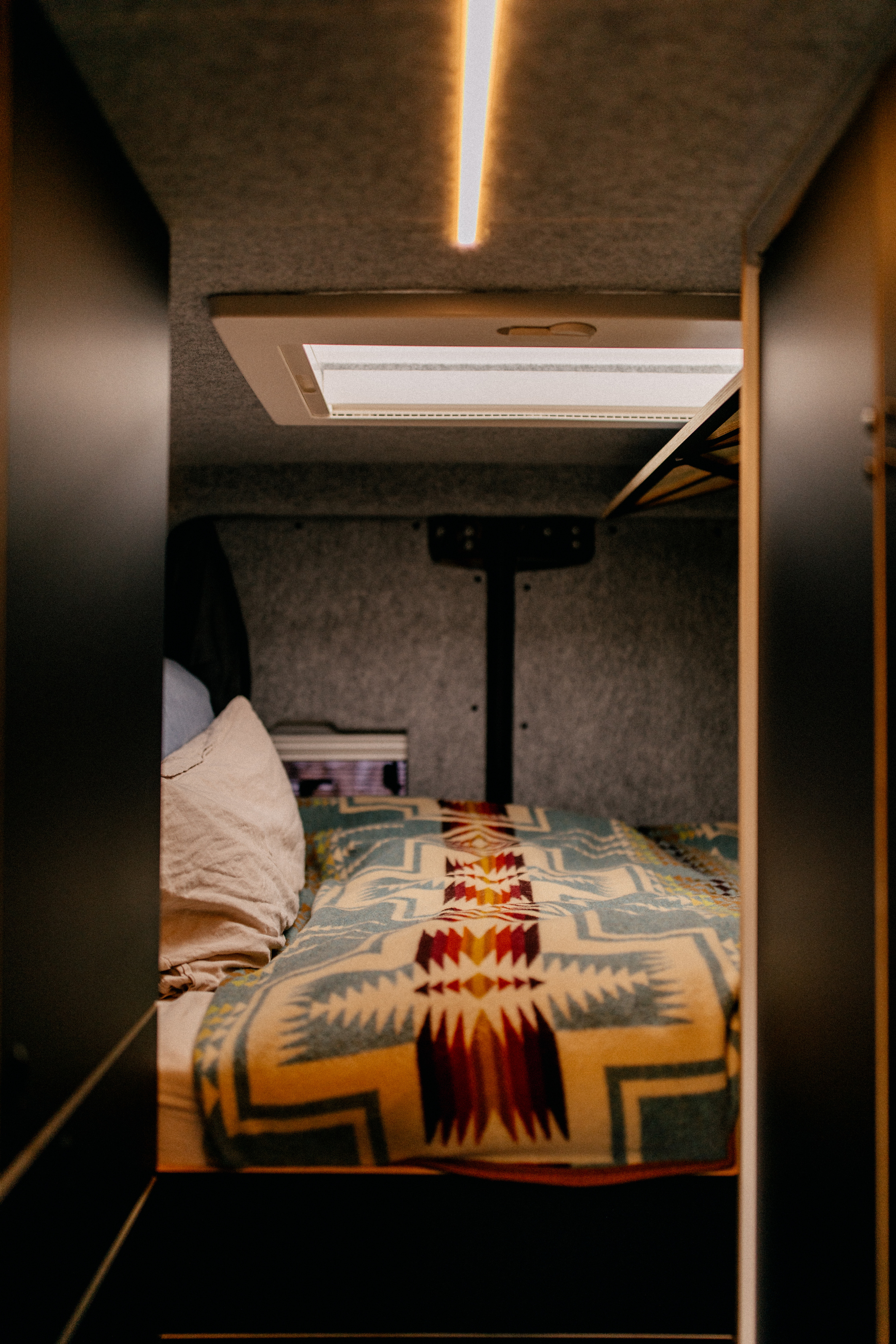 Querschläfer Bett in einem Design Campervan 202x130 cm auch für große Menschen geeignet. Wandverkleidung aus Schafwolle und Leinenbettwäsche. Aussicht auf die Sterne durch Dachluke. 